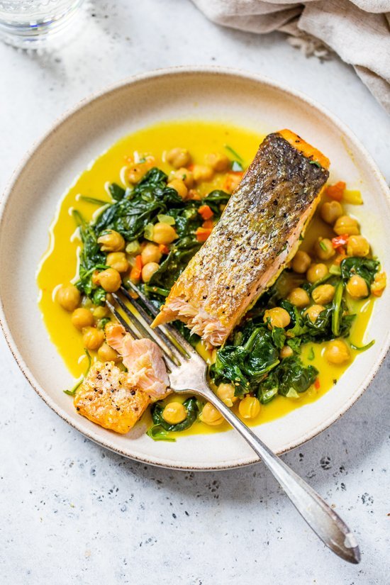 salmon on a plate with a fork, spinach and chickpeas