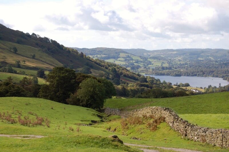 the green hilly countryside surrounding a lake in the Lakes District England