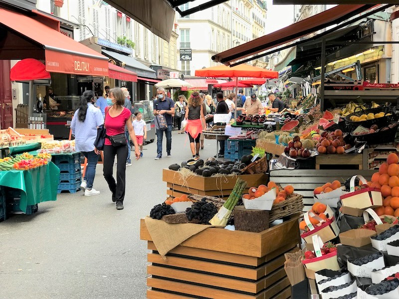 People walking through a street market selling fruit and vegetables