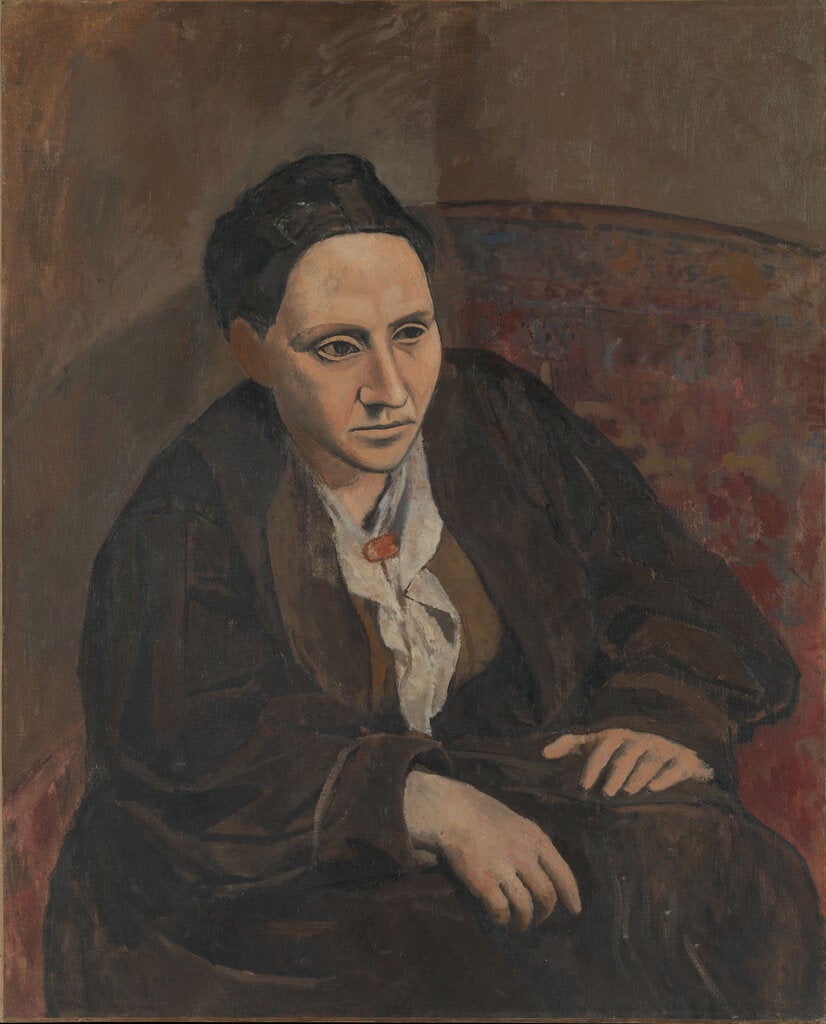 Picasso’s portrait of Gertrude Stein, flat, Cubist face, linebacker shoulders, dressed in her brown corduroy coat, white kerchief around her neck, brown background, hands on her knees.