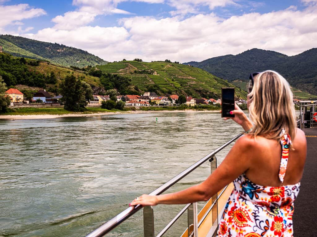 Woman on a river cruise taking photos of the scenery