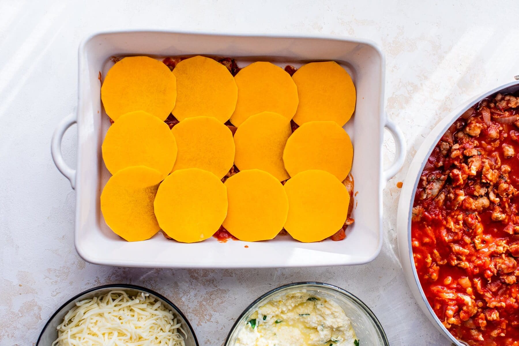 Butternut Squash in a casserole dish with marinara sauce and cheese