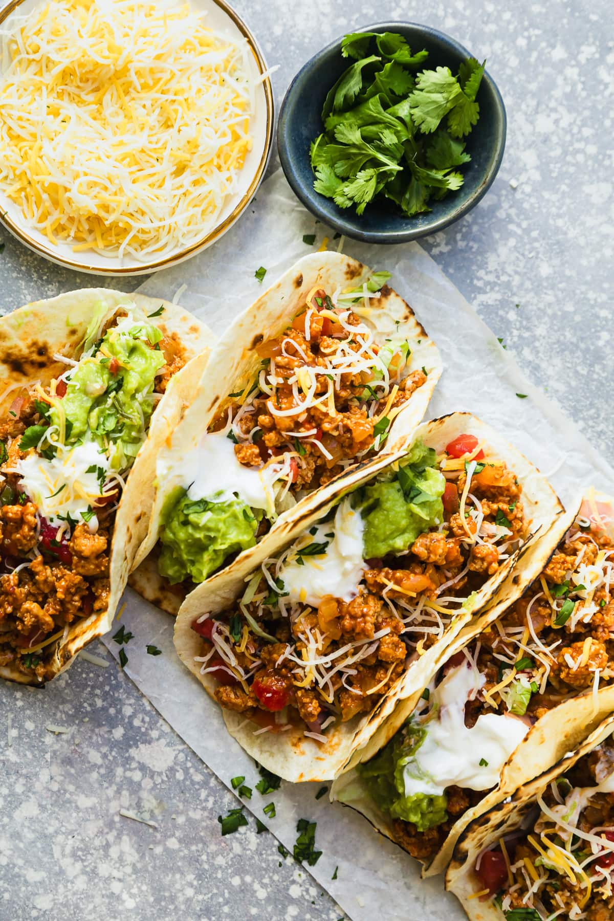 Tacos on a table with cheese and cilantro